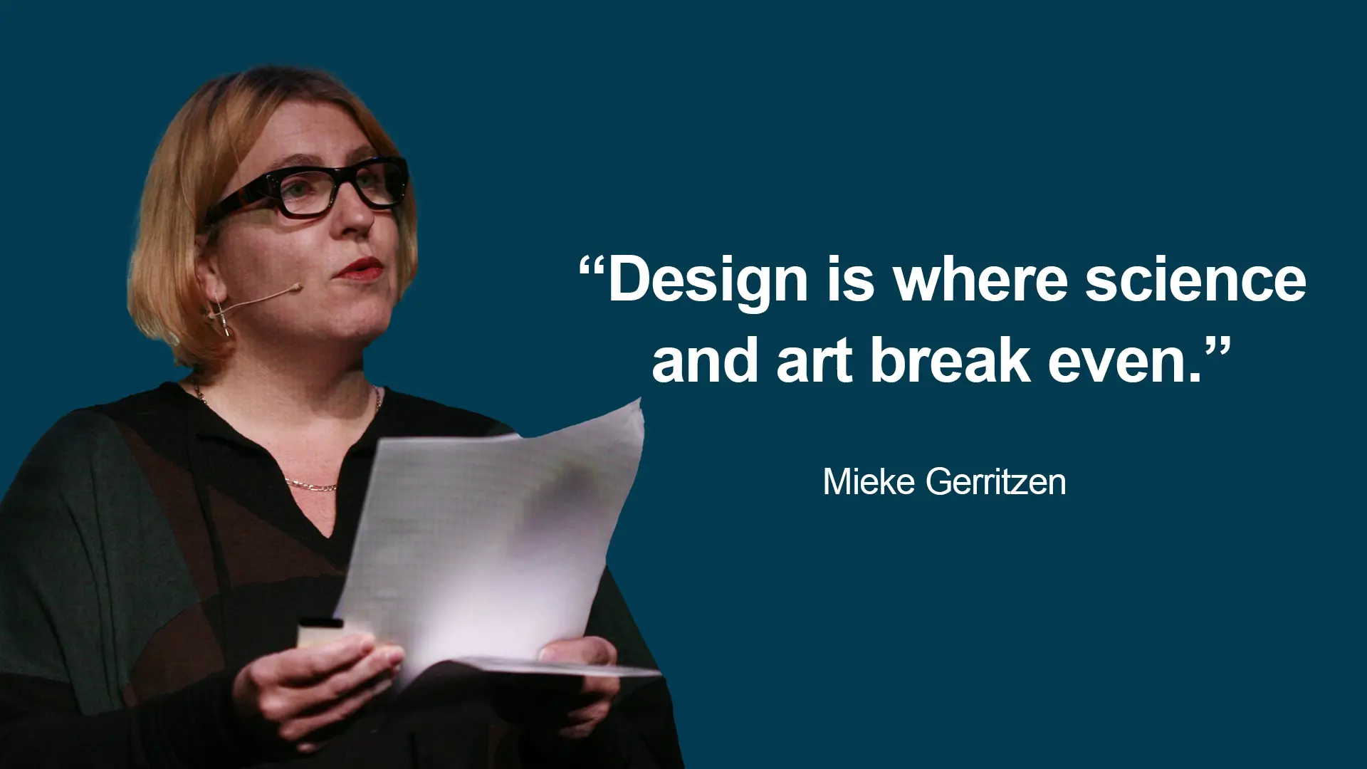 A woman holding papers and looking at the camera.