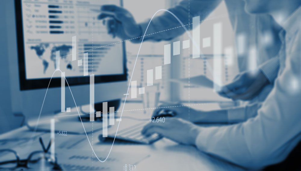 A person is working on a computer with graphs in the background.