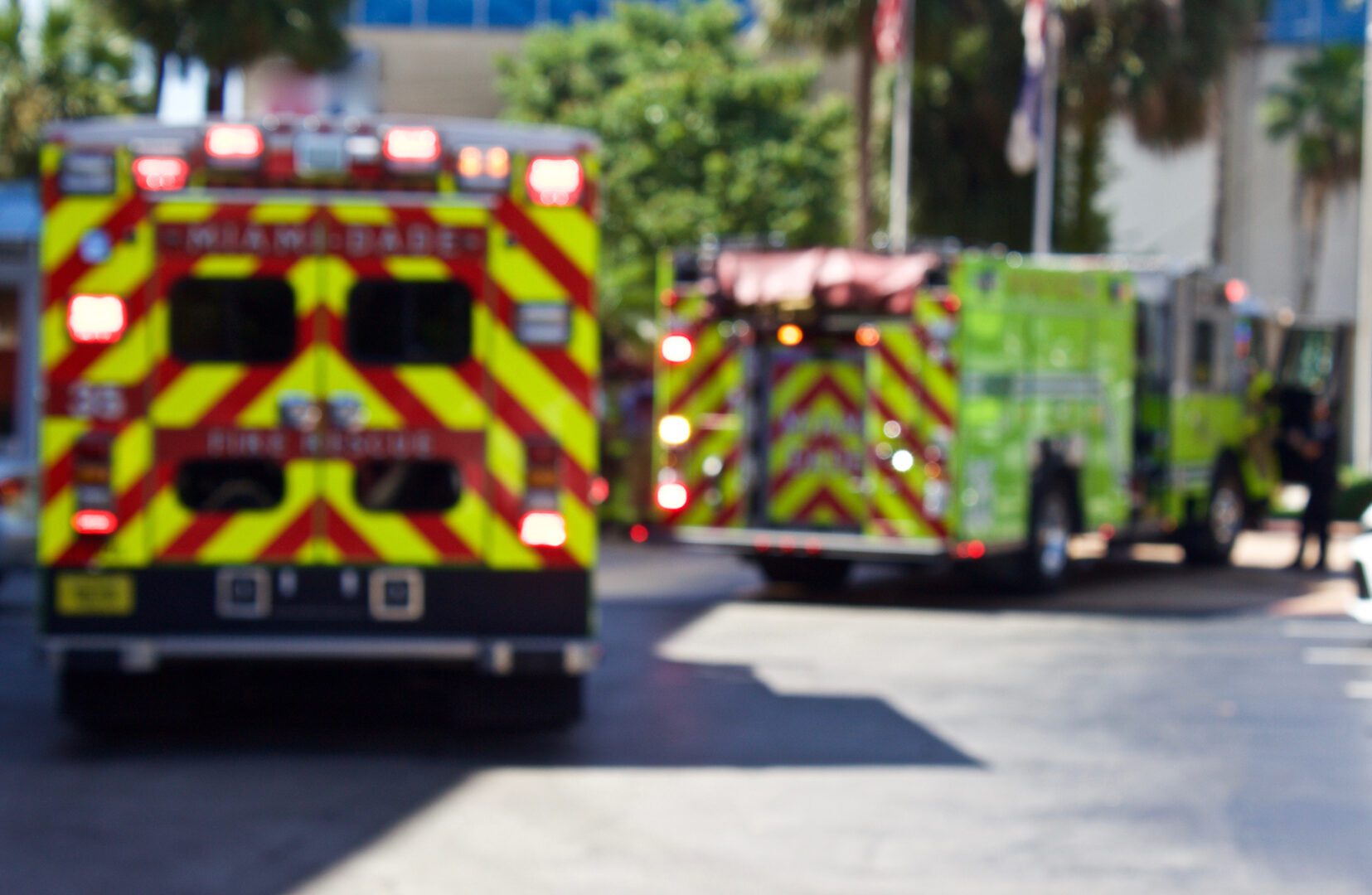 Two fire trucks are driving down the street.