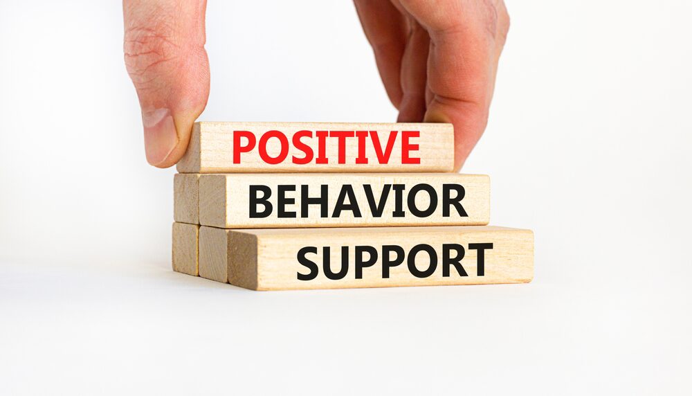A person is stacking blocks with the words positive behavior support.