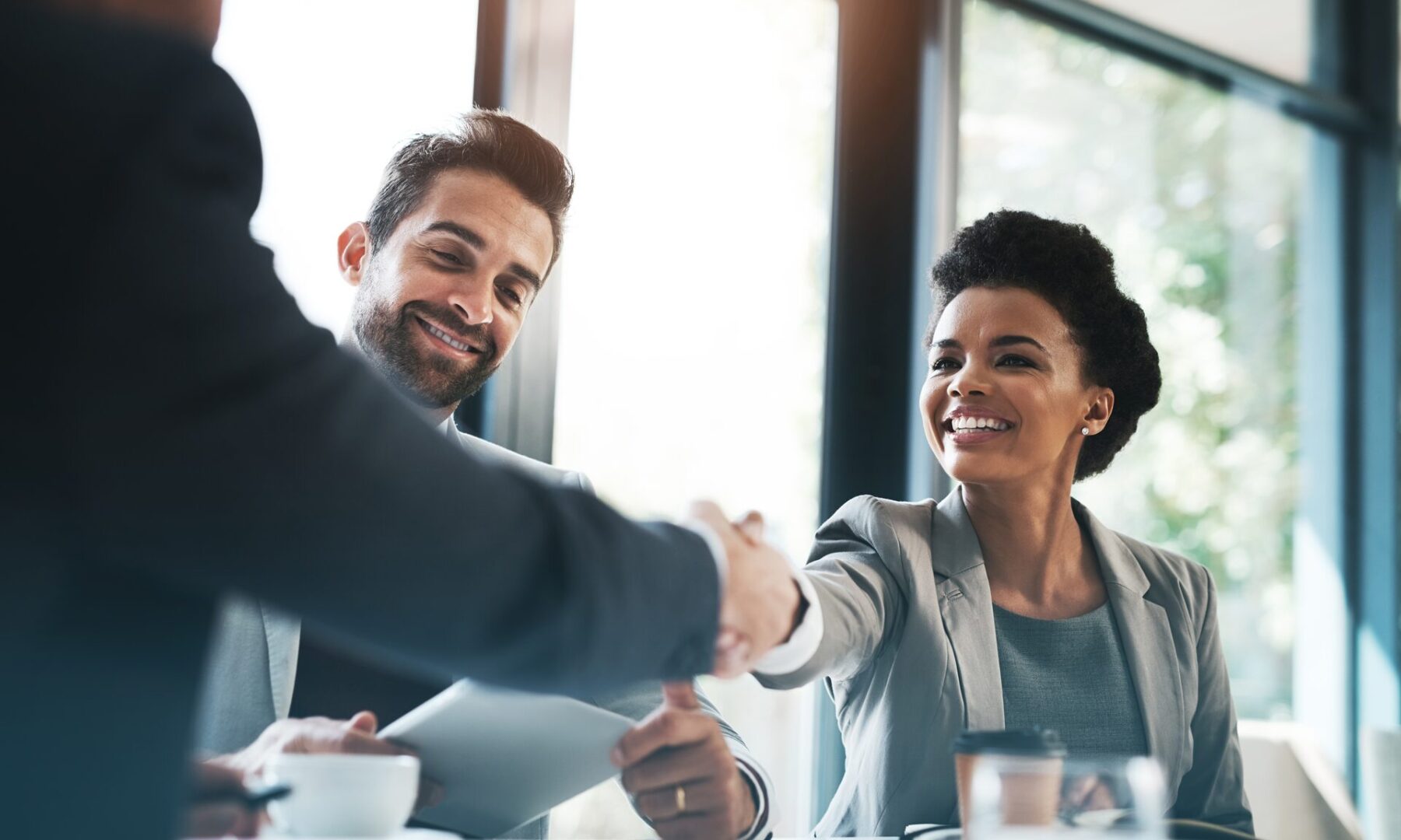 A man and woman shaking hands over a table.