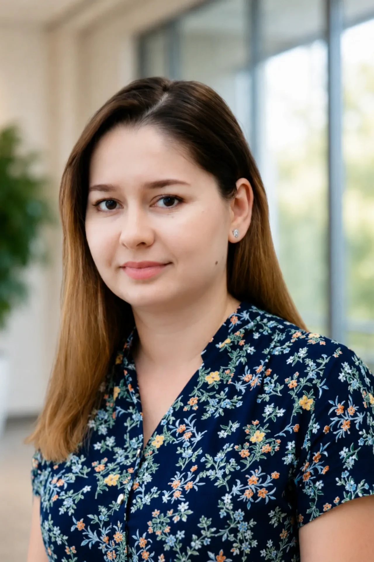 Portrait of a young woman with straight hair and floral blouse.